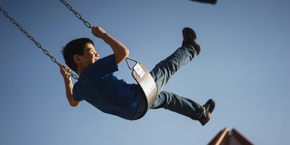 Happy child playing on a swing set.